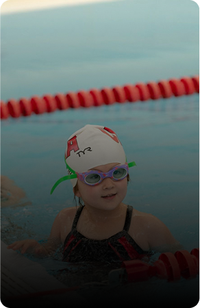 A young swimmer wearing goggles and a swim cap in a pool.
