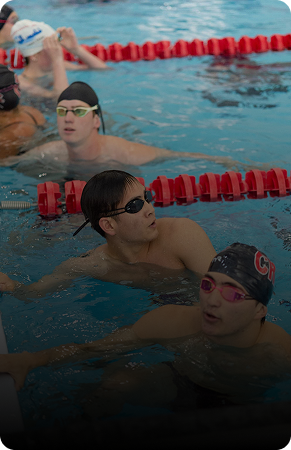 Three swimmers in a pool, preparing for a race or practice.