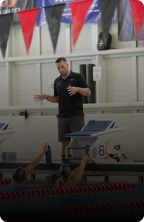 A coach instructing swimmers by the poolside.