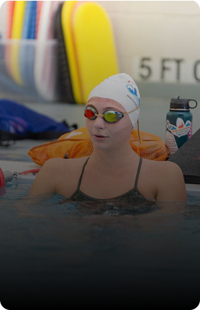 Swimmer wearing goggles and cap relaxes in the pool.