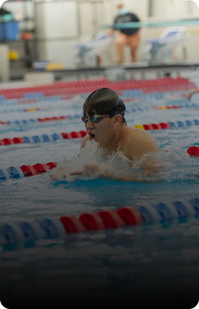A male swimmer in goggles competing in a pool race.