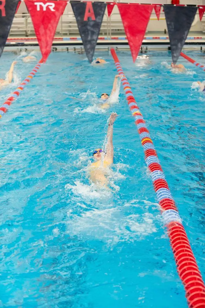 A swimmer performing the backstroke in a pool lane.
