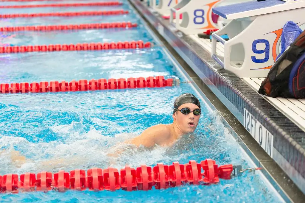 Swimmer in goggles finishes a race in the pool.