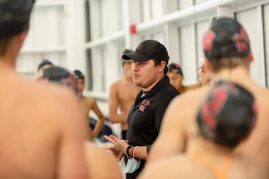 Coach giving instructions to swimmers during practice.