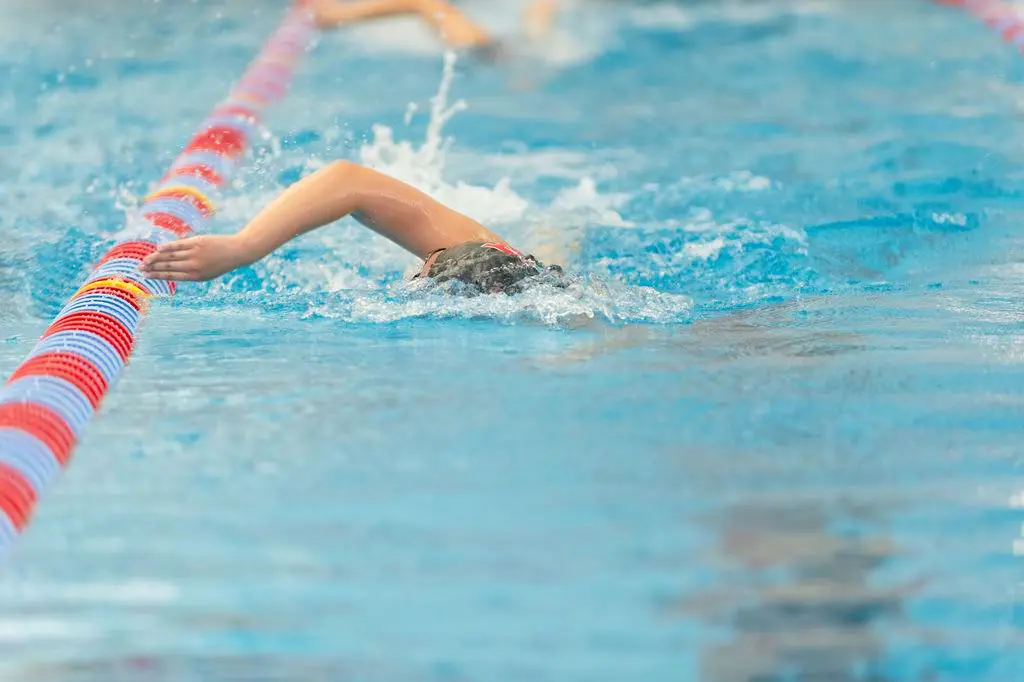 Swimmer performing freestyle stroke in a pool.