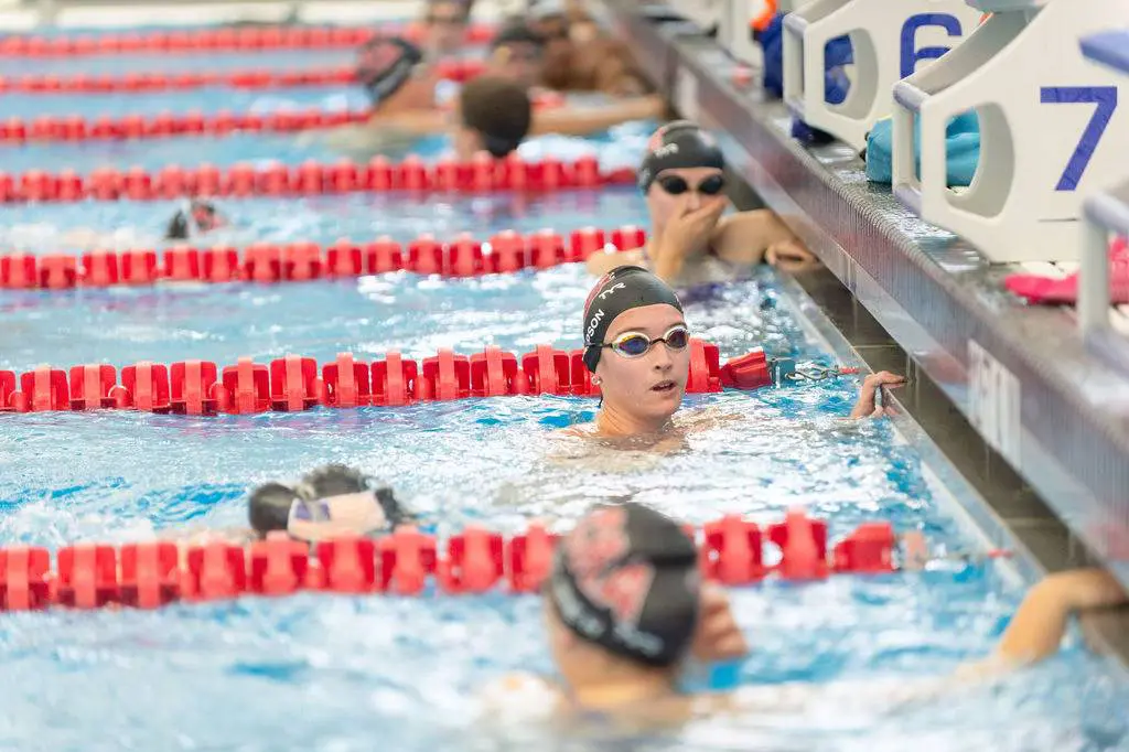 Swimmers resting at the pool edge during a swim meet.