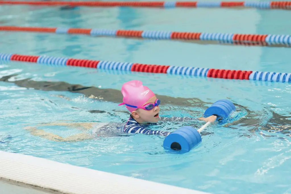 Child swimming with foam dumbbell in lane