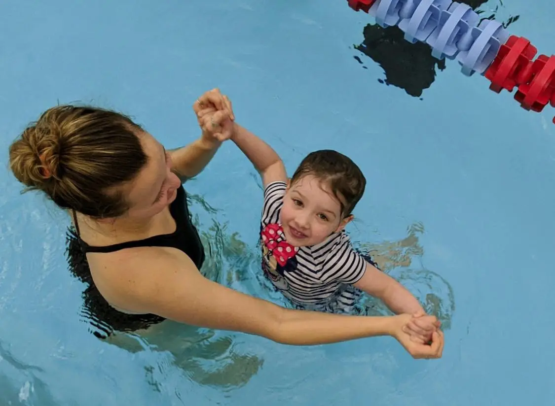 Child smiling while learning to swim.