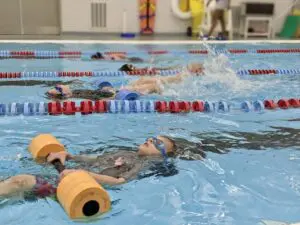 Children practicing swimming techniques in pool.