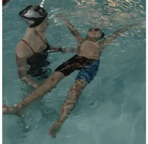 Child floating in water during lesson.