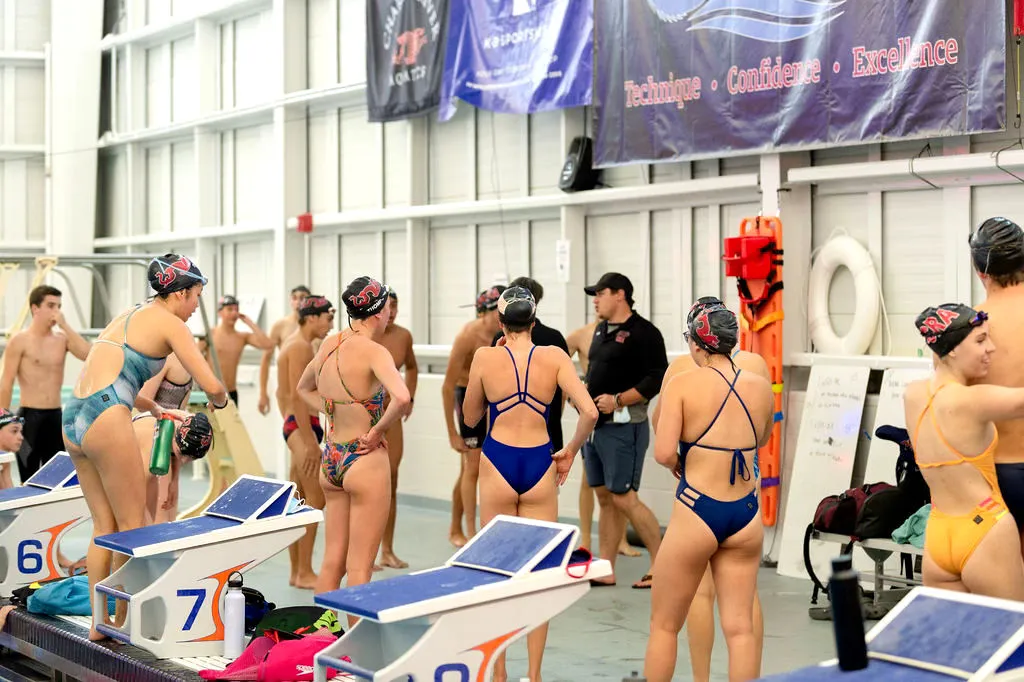 Swimmers prepare for a race at an indoor pool.