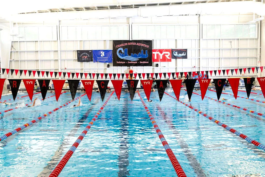 Indoor swimming pool with lanes marked by red and black flags and lane ropes.