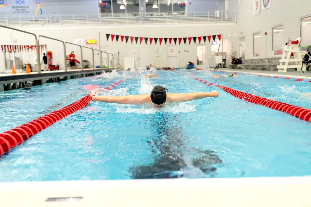 Swimmer gliding in pool lanes during practice.