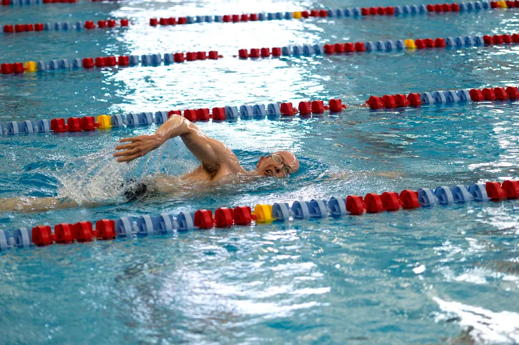Swimmer performing freestyle in a competition pool with lane dividers.