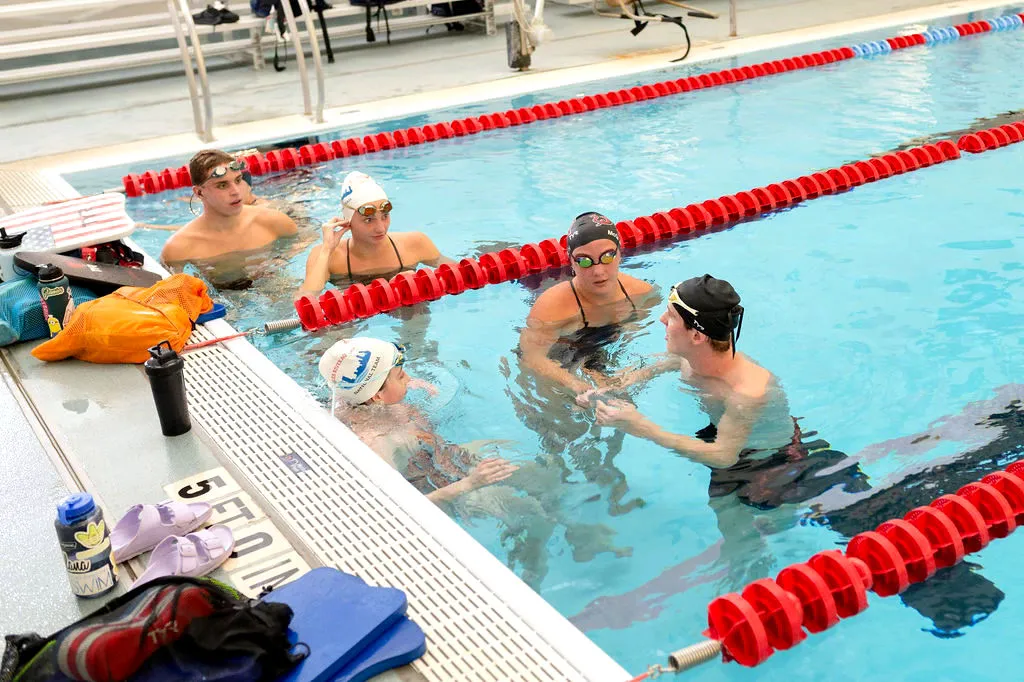 Swimmers gather at the pool edge during a practice session.