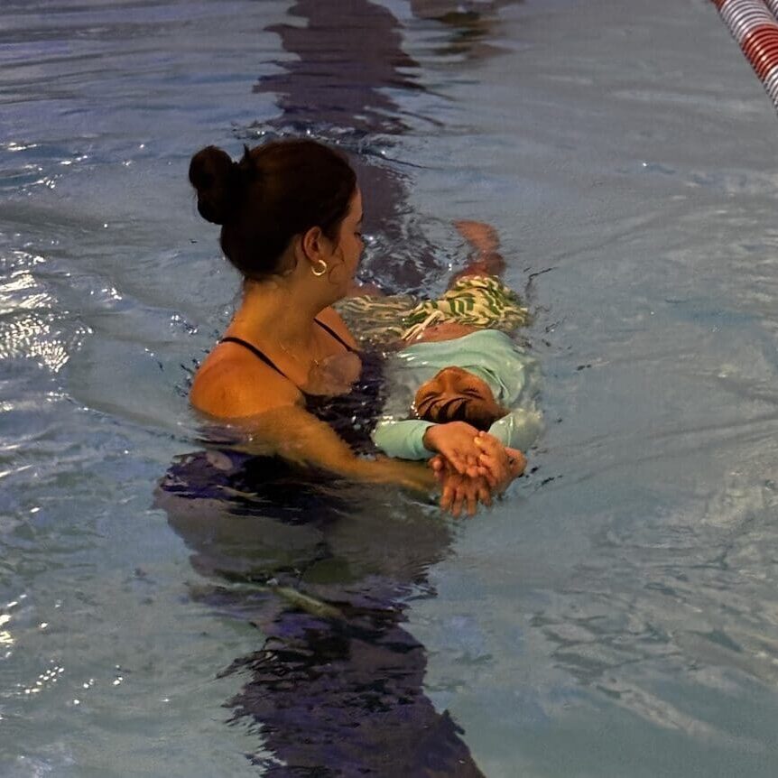 Instructor guiding child in water